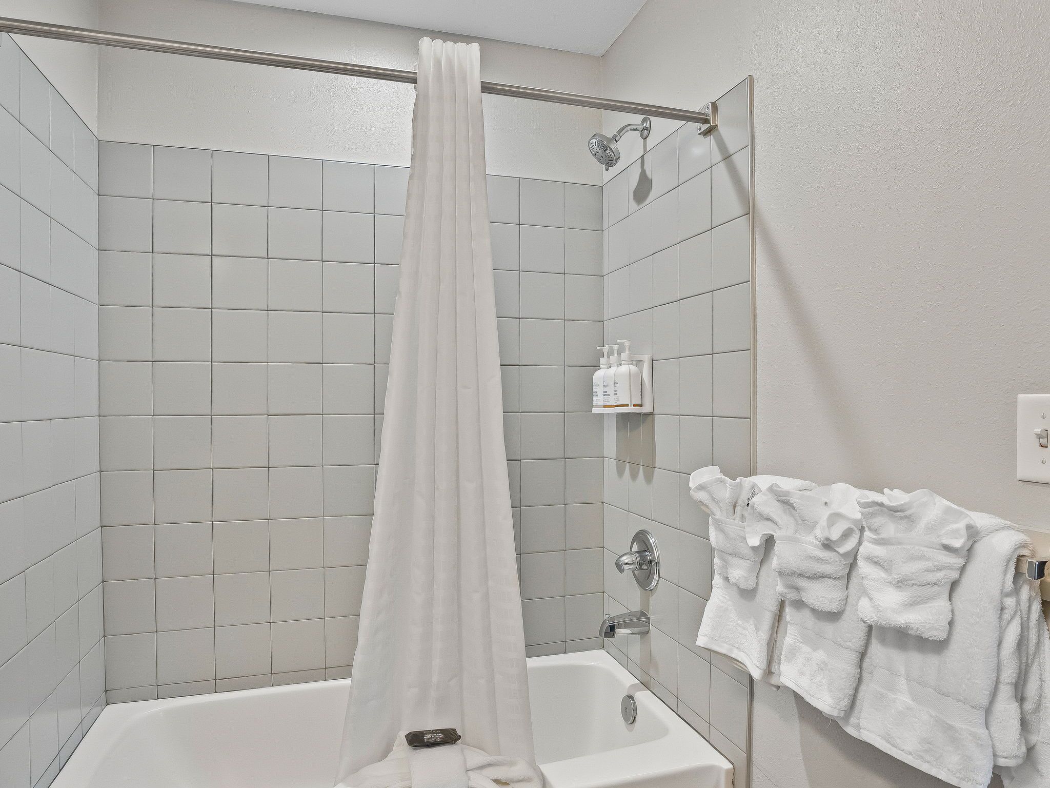 A bathroom with a shower, a bathtub, and a towel rack with towels.