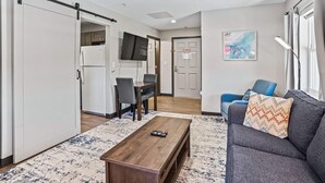 En moderne stue med sofa, sofabord og fjernsyn ophængt på væggen.