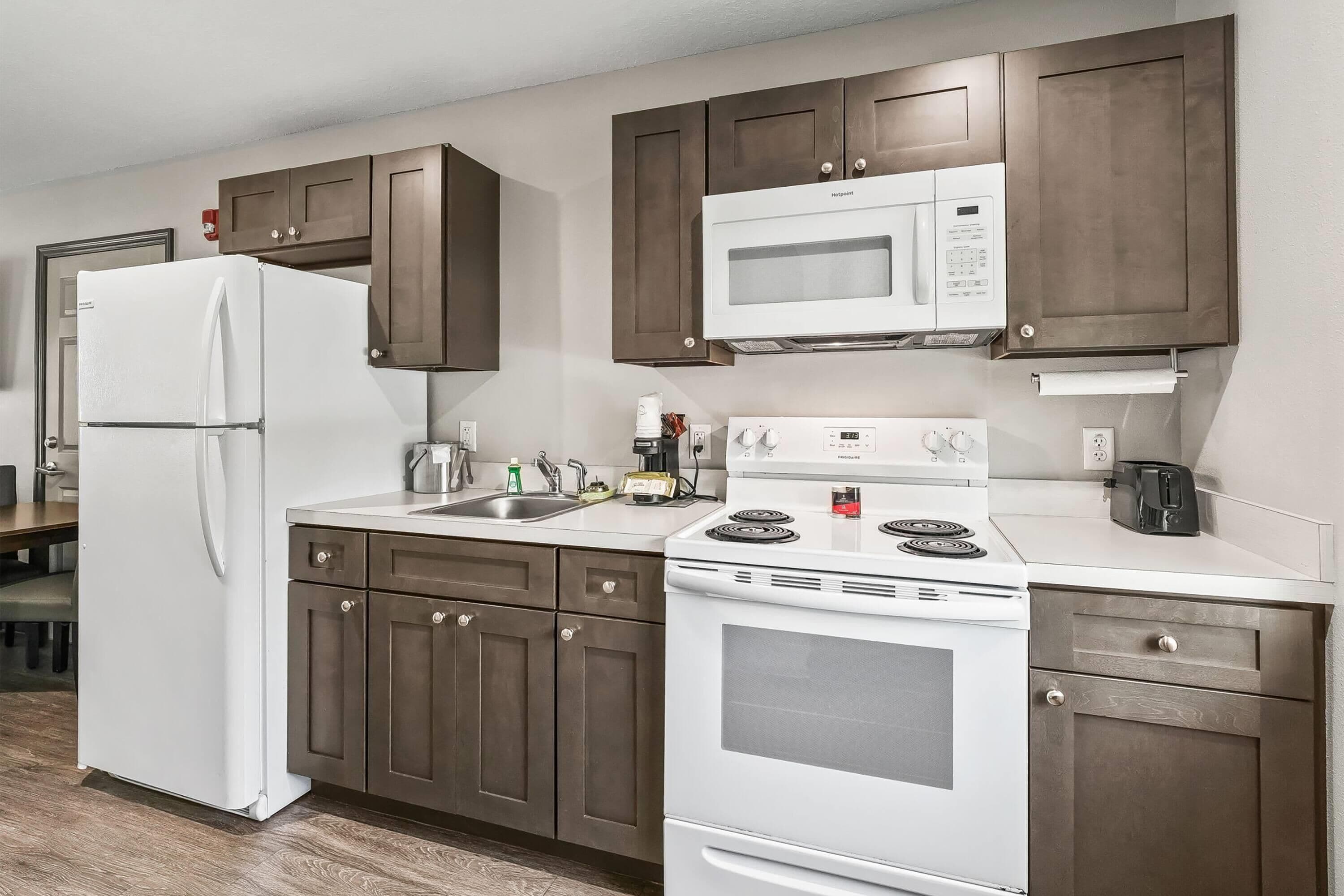 A modern kitchen with a refrigerator, microwave, stove, and cabinets.