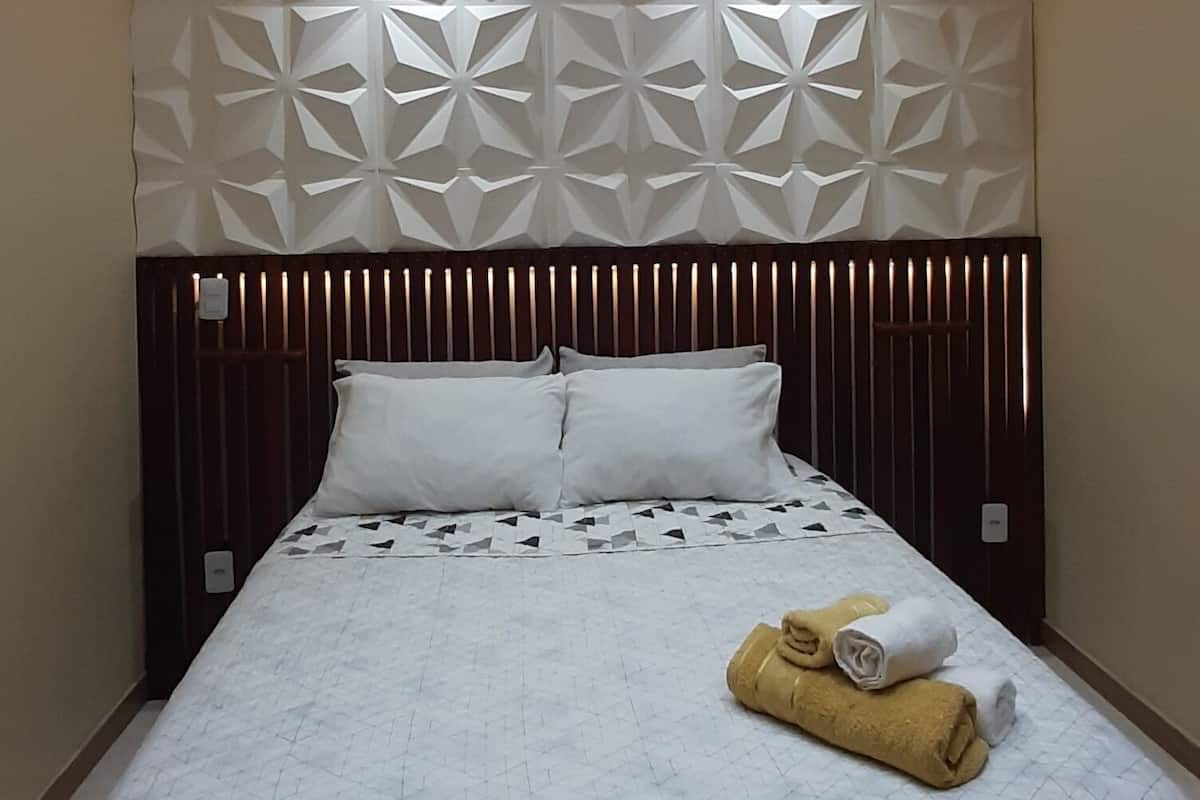 Ein Hotelzimmer mit Bett, Kopfteil und Deckenleuchten.
