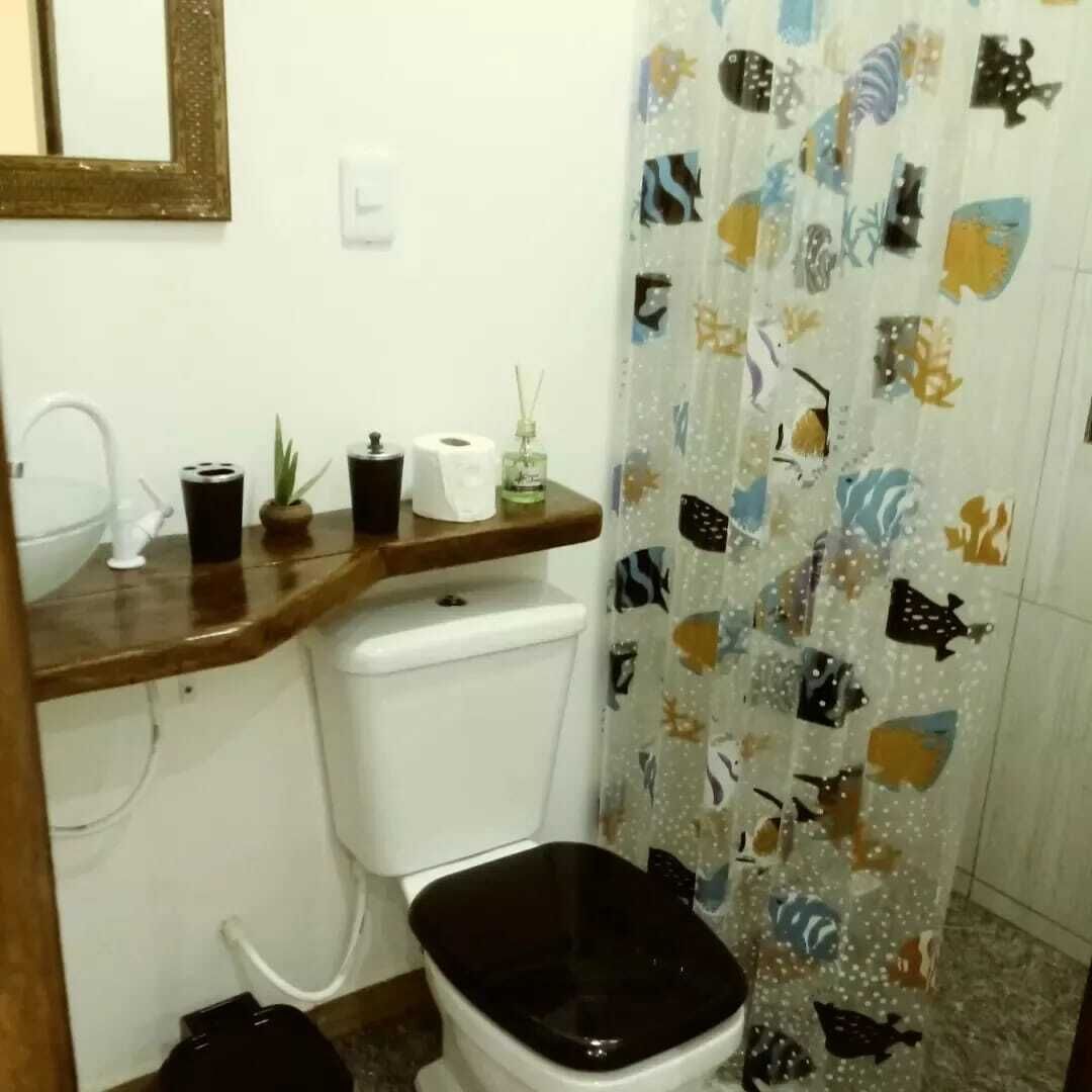 A bathroom with a toilet, a sink, a mirror, and a shower curtain with fish patterns.