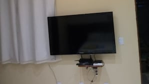 A room with a mounted flat-screen TV, an air conditioning unit, and a power outlet on the wall. - Chalés Pôr do Sol Gostoso (São Miguel do Gostoso)
