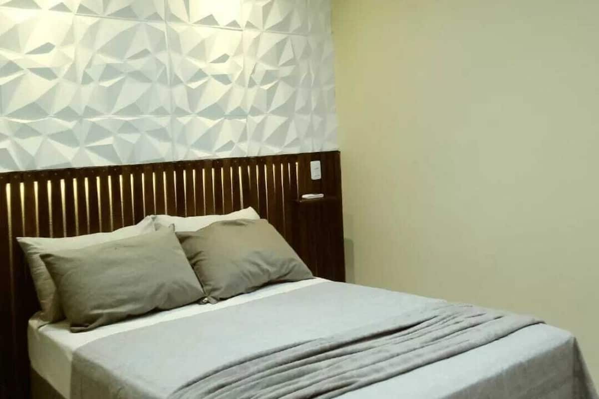 Ein Schlafzimmer mit Bett, Kissen und einer Wand mit Struktur.