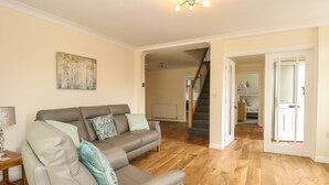 A living room with a grey sofa, wooden flooring, and a staircase leading to another room. - Fallowfield (Great Yarmouth)