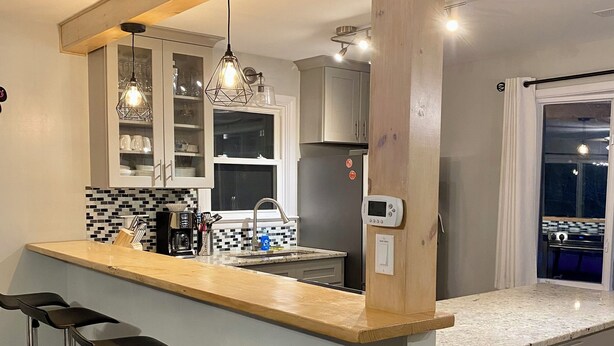 Una cocina moderna con barra, electrodomésticos de acero inoxidable y taburetes de bar.