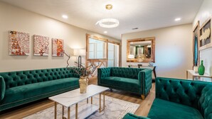 A spacious living room with a green sofa set, a marble coffee table, and decorative wall art. - Stylish and funky, minutes away from everything NWA has to offer! (Springdale)