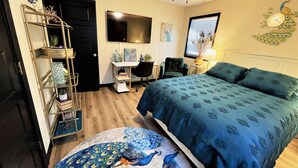 A bedroom with a bed, a desk, a chair, a peacock-themed rug, and a wall clock. - Stylish and funky, minutes away from everything NWA has to offer! (Springdale)