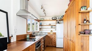 A kitchen with wooden cabinets, a stainless steel sink, and a white refrigerator. - Emily's Beach House - Kaiteriteri Holiday Home (Kaiteriteri)