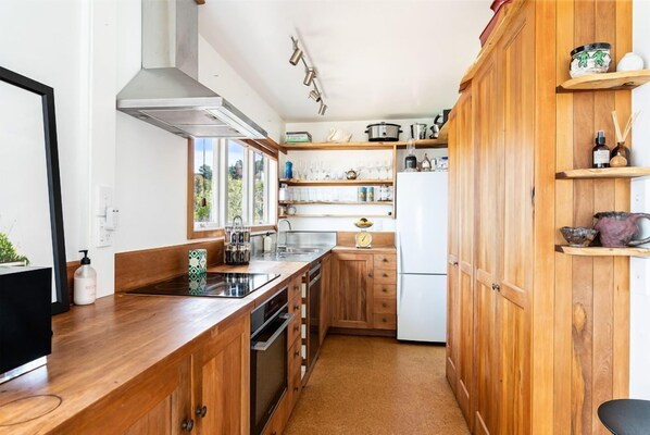 A kitchen with wooden cabinets, a stainless steel sink, and a white refrigerator.