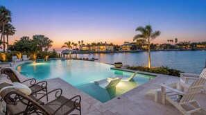 A swimming pool with lounge chairs, a view of a waterfront, and a building in the background. - Exceptional Waterfront Home in Sarasota!! (Sarasota)