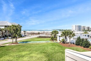 A residential area with a swimming pool, palm trees, and a view of the beach and ocean.