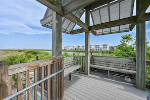A wooden deck with benches and a metal railing overlooking a body of water and buildings in the distance.
