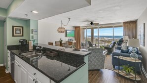 Una cucina moderna con una grande isola, un'area pranzo con vista e un soggiorno con divano e televisione.