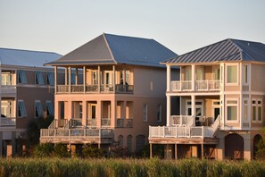 Une propriété située en bord de mer, dotée de plusieurs balcons, d’une terrasse couverte et d’une structure à deux étages.