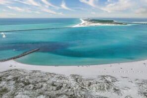 Eine Küstenlandschaft mit Strand, Steg und Leuchtturm.