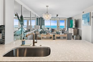 Una cocina moderna con un lavamanos grande, comedor con sillas y vistas al océano.