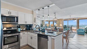 A modern kitchen with stainless steel appliances, a large island, and a view to the outdoors.