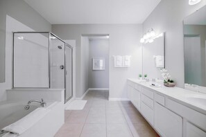 A modern bathroom with a glass-enclosed shower, a large vanity with a mirror, and a walk-in shower. - Vista Cay Lakeview Elysium. Walk to Epic Universe and the OCCC (Orlando)