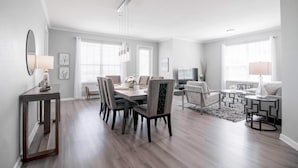 A modern living room with a dining area, featuring a large table, comfortable seating, and a neutral color palette. - Vista Cay Lakeview Elysium. Walk to Epic Universe and the OCCC (Orlando)