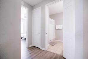A hallway with white doors leading to a bathroom with a shower and a towel rack. - Vista Cay Lakeview Elysium. Walk to Epic Universe and the OCCC (Orlando)