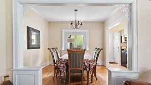 A dining room with a white table, four chairs, and a chandelier.