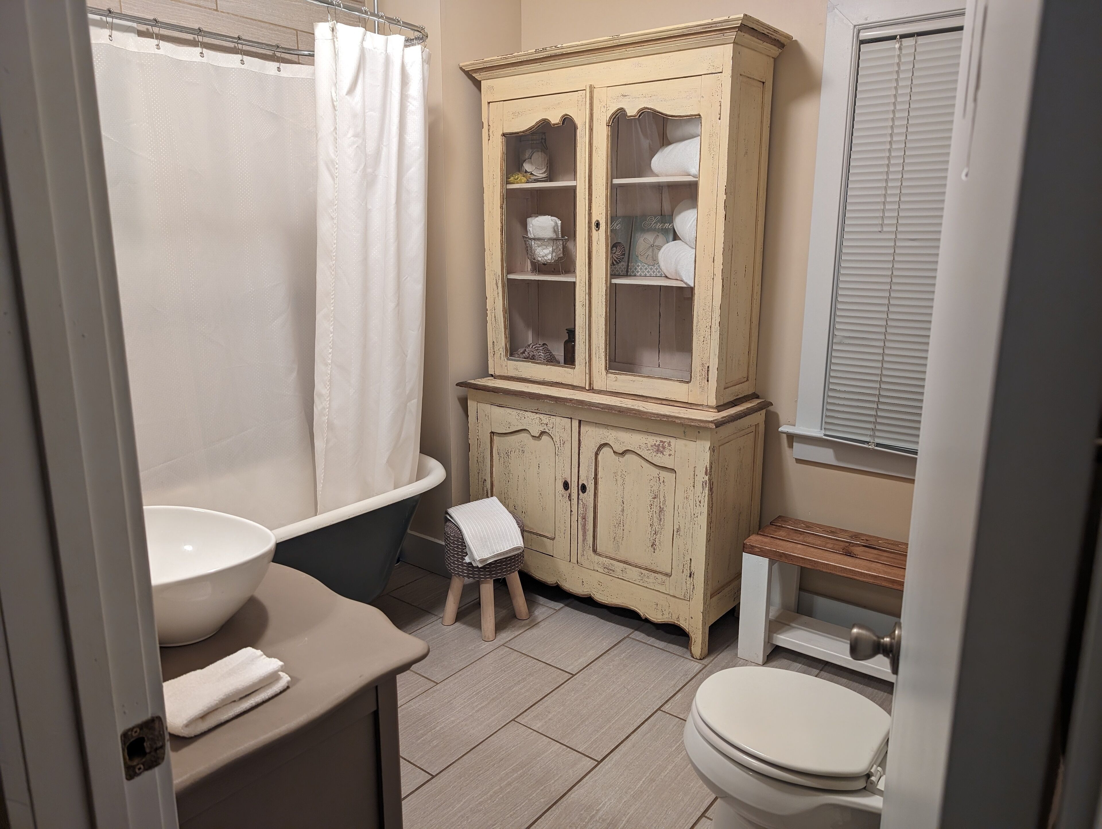 A bathroom with a bathtub, a sink, a toilet, and a cabinet with glass doors.