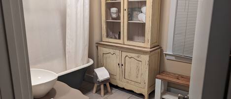 A bathroom with a bathtub, a sink, a toilet, and a cabinet with glass doors.