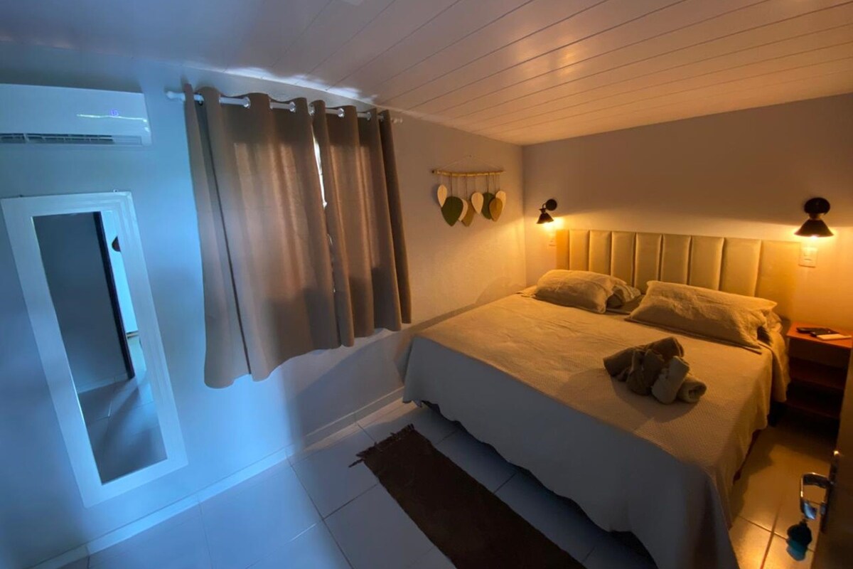 A bedroom with a bed, curtains, a wall-mounted light, and a small rug.