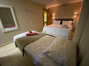 A hotel room with two beds, a mirror, and a wall-mounted light fixture.