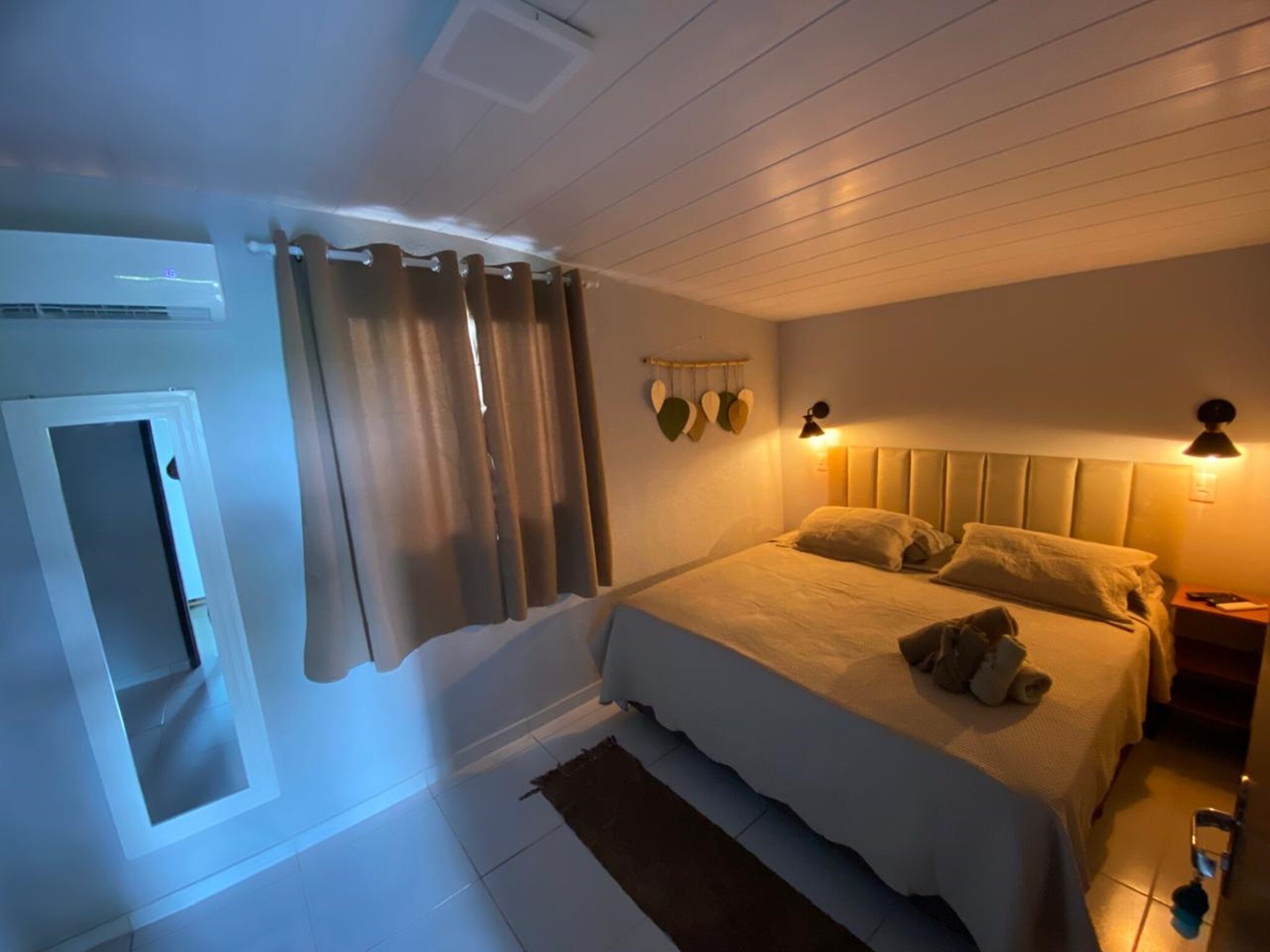 Una camera da letto con un letto, tende, una lampada a parete e un piccolo tappeto.