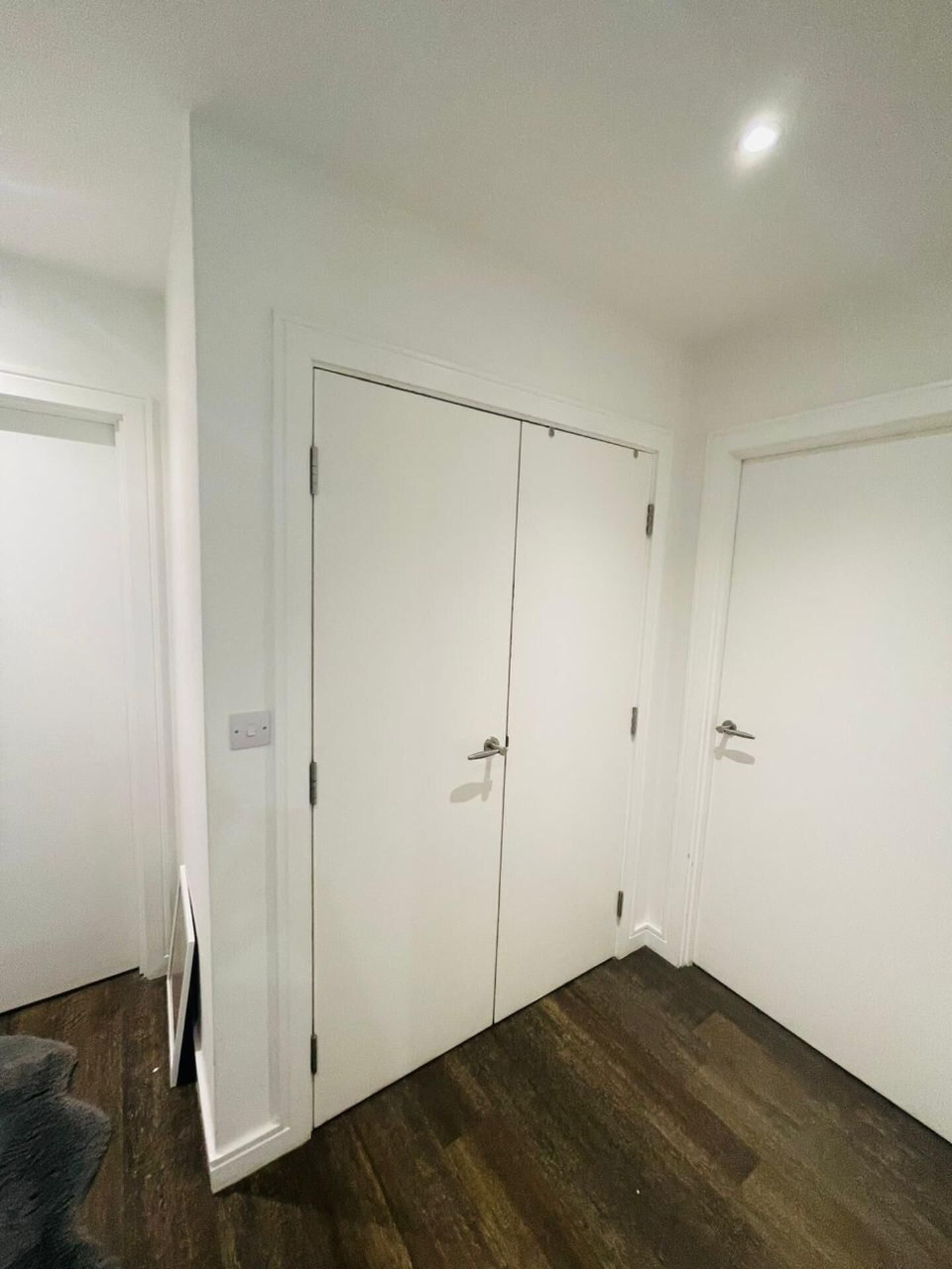 A room with a large white wardrobe, a wooden floor, and a white door.