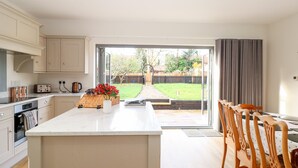 Une cuisine moderne avec un îlot central, des chaises en bois et une vue sur le jardin.
