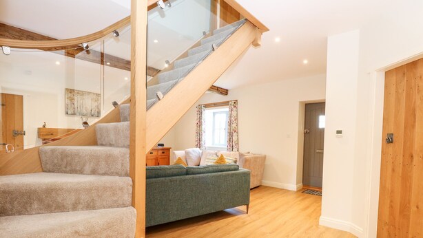 Un intérieur moderne avec un escalier en bois, un canapé vert et un plancher en bois.