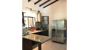 Una cocina con encimera de granito, electrodomésticos de acero inoxidable y armarios de madera oscura.