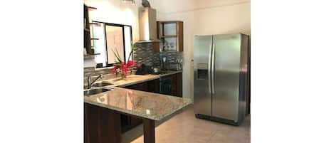 A kitchen with a granite countertop, stainless steel appliances, and dark wooden cabinets.