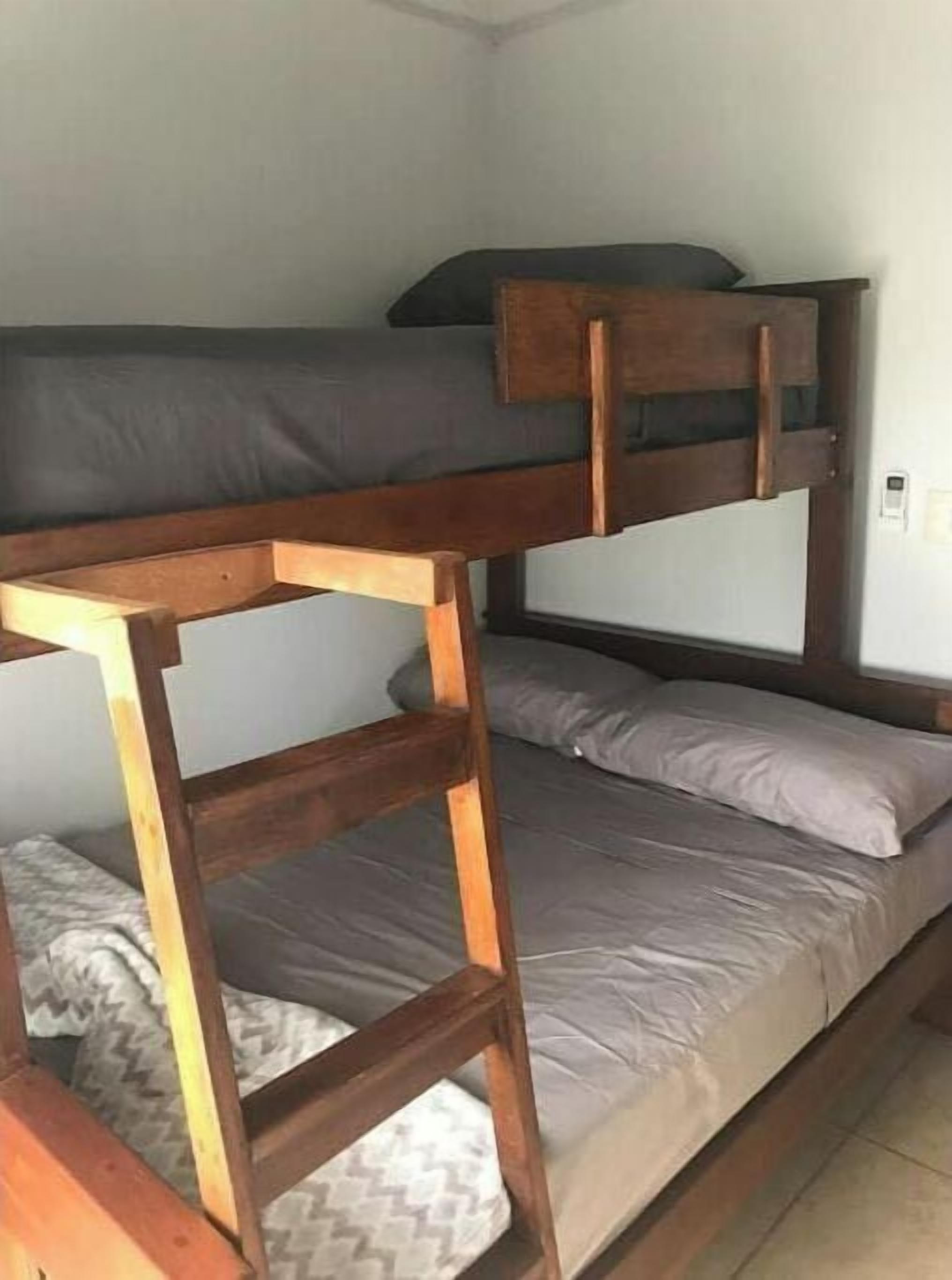 A bunk bed with wooden frames and grey bedding.