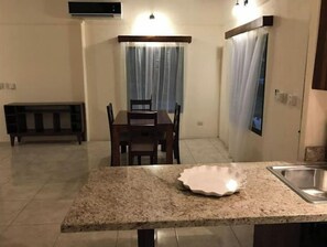 A compact kitchen with a granite countertop, a sink, and a dining area with a table and chairs.