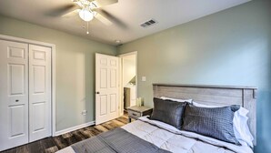 Un dormitorio con cama, mesita de noche, ventilador de techo y puerta.