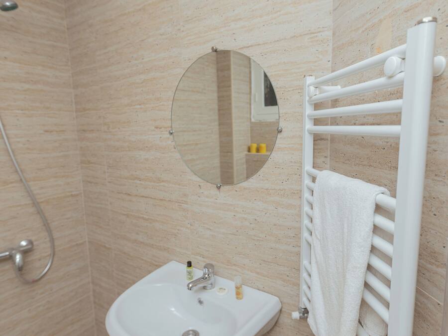 Un baño con lavamanos, espejo, toallero y ducha.
