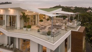 A modern, multi-level residential building with a spacious outdoor patio area featuring seating and a dining setup. - Luxury Apartments - VIP All-inclusive (Puerto Plata)