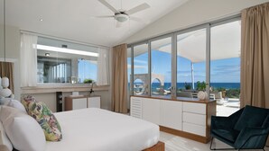 A modern hotel room with a large bed, a desk, and a view of the ocean. - Luxury Apartments - VIP All-inclusive (Puerto Plata)