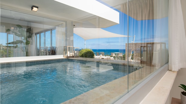 A modern infinity pool with clear blue water, surrounded by glass walls and a white ceiling. - Luxury Apartments - VIP All-inclusive (Puerto Plata)