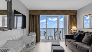 A modern living room with a sofa, a TV, a balcony with chairs, and a table.
