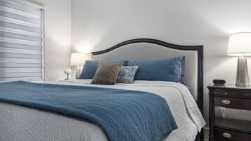 A neatly made bed with a blue blanket, a headboard, and two bedside lamps.