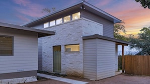 A modern two-story house with a stone facade, a front door, and a wooden fence.