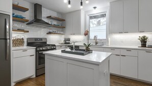 A modern kitchen with white cabinetry, stainless steel appliances, and a central island.