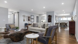 A spacious living room with a sofa, armchairs, a coffee table, and a dining area with a table and chairs.