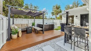 A patio with a sofa, chairs, a table, and a barbecue area.