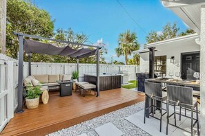 A patio with a sofa, chairs, a table, and a barbecue area. - Bungalow! Hot TUB! Games! 10 min to Beach! (Palm Beach County)