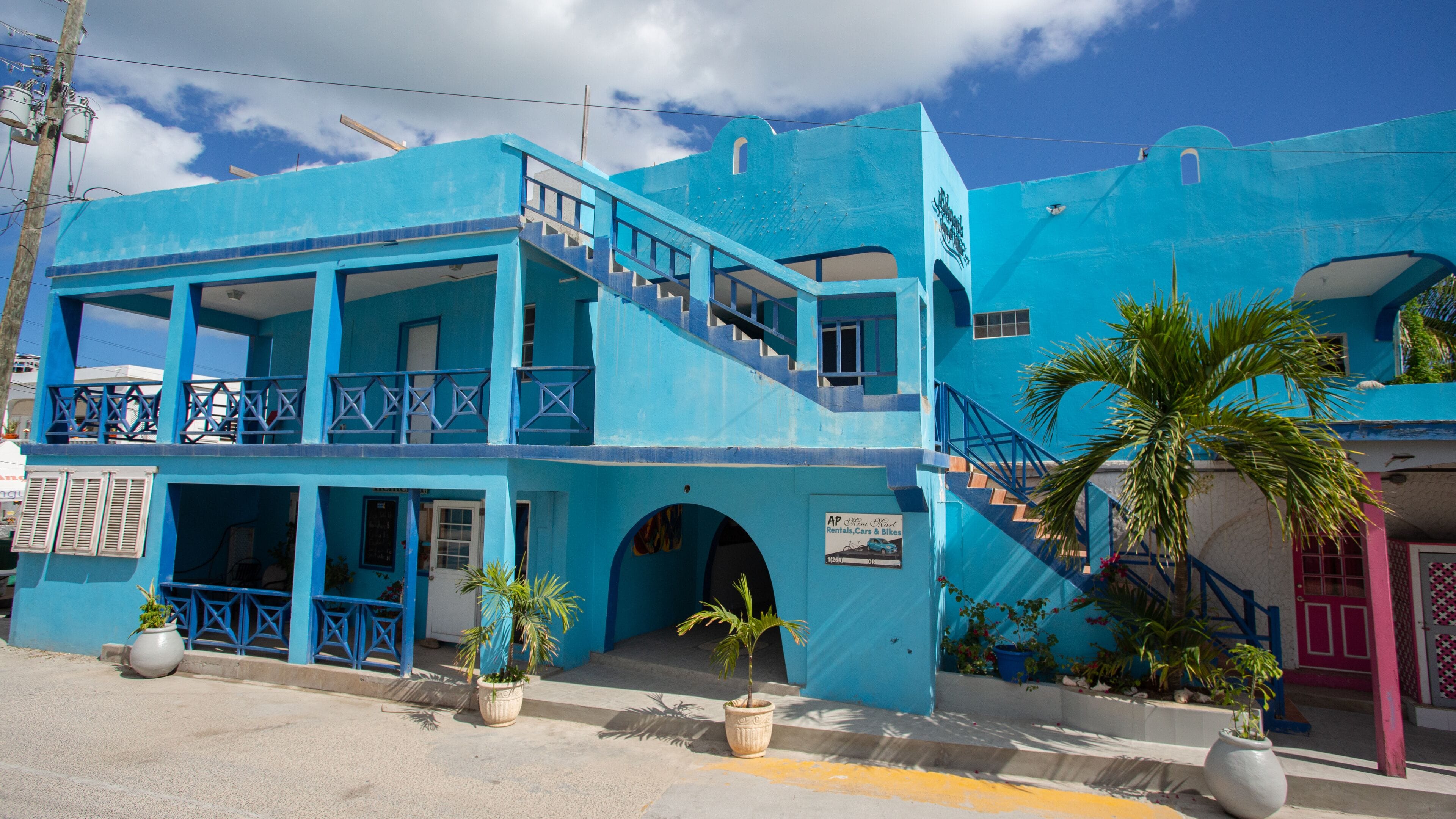 A two-story building with a blue exterior, a balcony, and a staircase leading to the upper floor.